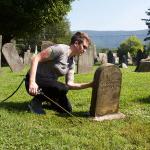 Caitlin Abrams’08 uses D2, a non-toxic biocide, to clean gravestones.